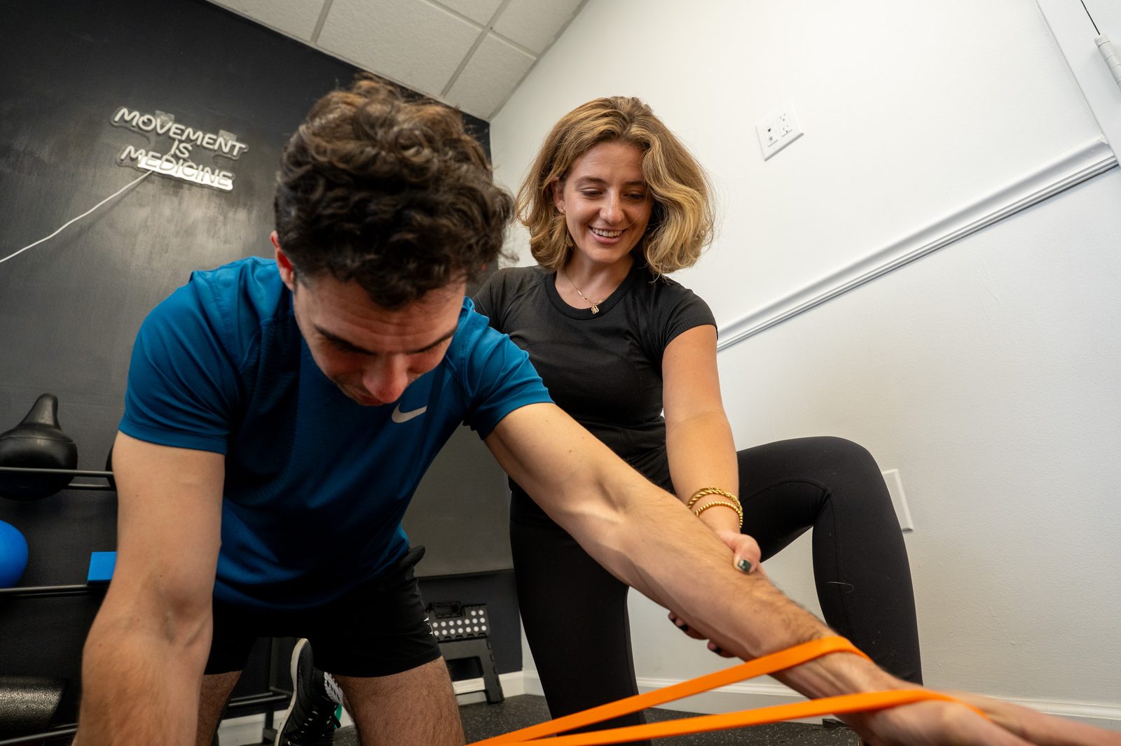 Erica coaching an athlete through a banded core exercise in the gym