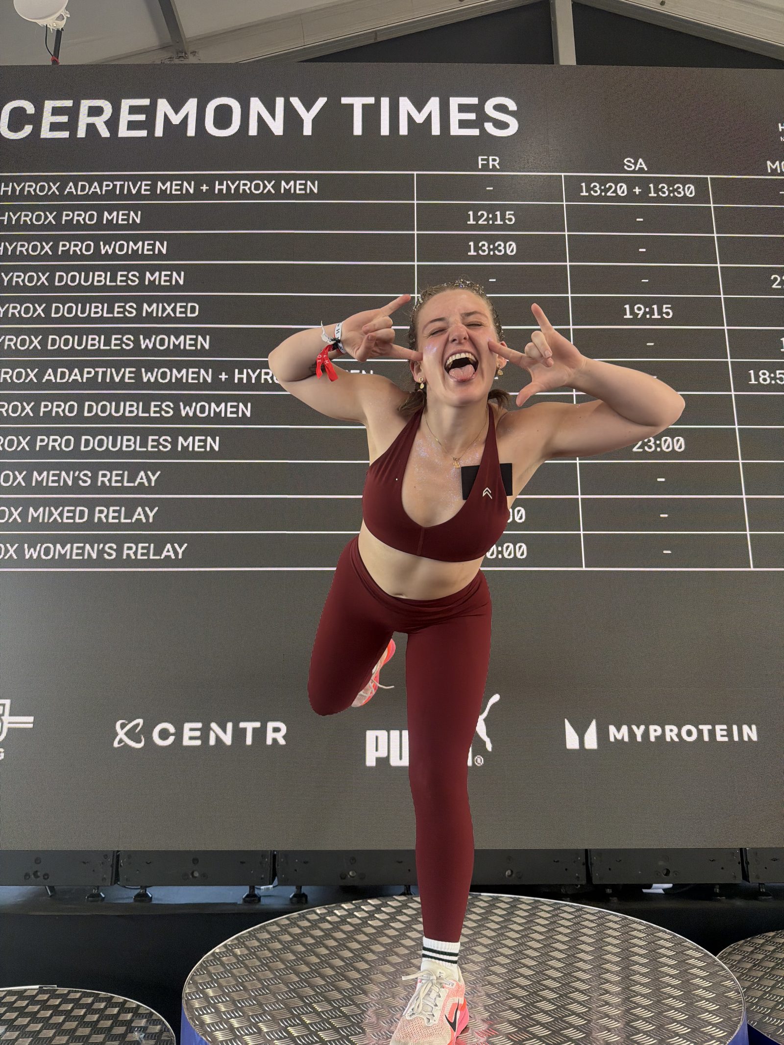 Erica celebrating on the podium at HYROX New York in her maroon race kit