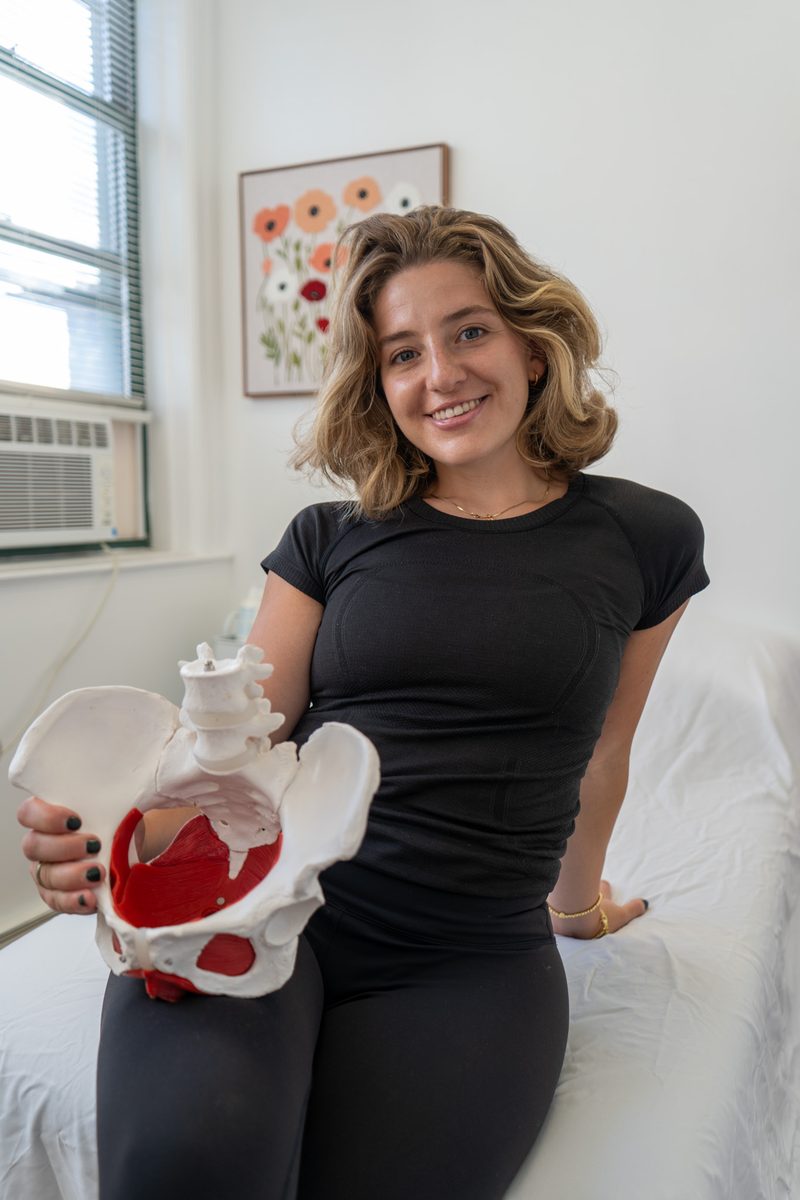 Erica holding a pelvic model, explaining anatomy the way she does on a virtual session